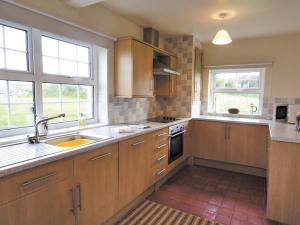 a kitchen with wooden cabinets and a sink at Riffli - Hw7700 in Abersoch