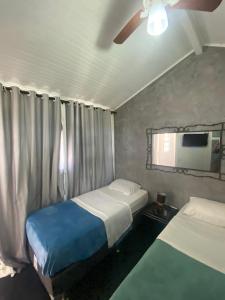 a bedroom with two beds and a tv on the wall at Tao in Búzios