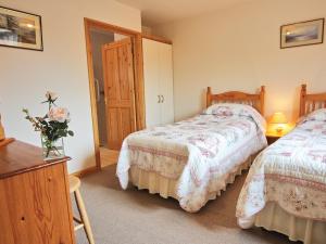 a bedroom with two beds and a table with a vase of flowers at Bridle Cottage in Hoarwithy