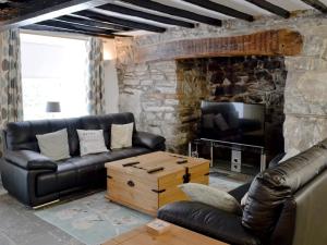 a living room with a leather couch and a tv at Pendref in Trawsfynydd