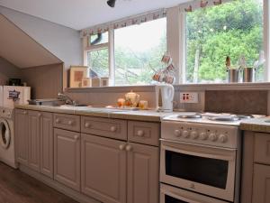 a kitchen with a stove and a sink and a window at Hendy in Waenfawr