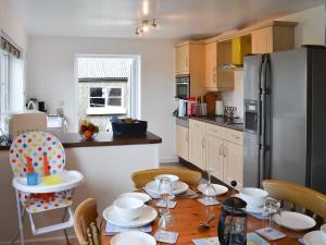 a kitchen with a table with chairs and a refrigerator at Rhos Y Grug in Llangwnadl