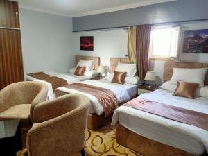 una habitación de hotel con 3 camas y una silla en فاكانزا شقة فندقية مفروشة- vacanze en Fayoum