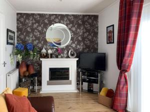 a living room with a fireplace and a mirror at Beach Cottage in Gairloch