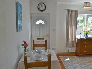 a dining room with a table and a clock on the wall at Little Tamarisk in Padstow