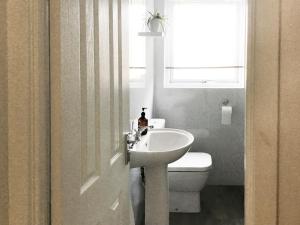 baño con lavabo y aseo y ventana en Beach Cottage, en Gairloch