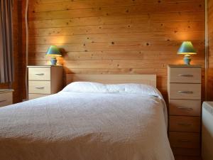 a bedroom with wooden walls and a bed with two lamps at The Cabin in Wendling
