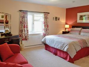 a bedroom with a bed and a chair and a window at Maes-yr-adwy in Abergorlech