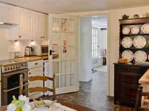 a kitchen with white cabinets and a counter top at Peartree Cottage in Northlew