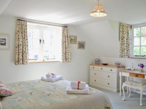 a bedroom with a bed and a desk and windows at Peartree Cottage in Northlew