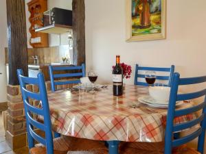 Quince Cottage - 27443 في Sedlescombe: طاولة غرفة الطعام مع كؤوس النبيذ والكراسي الزرقاء