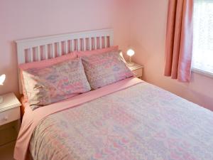 a bedroom with a bed with a pink comforter and pillows at Silver Birches-af46 in Horning