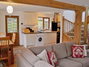 a living room with a couch and a kitchen at Dove Cottage in Ampney Crucis