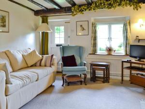 a living room with a couch and a chair and a television at Rose Cottage in Chipping Campden