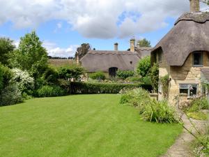 a yard of an old house with a grass lawn at Rose Cottage in Chipping Campden