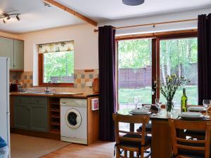 a kitchen with a dishwasher and a table with chairs at Squirrel Cottage in Kilmuir