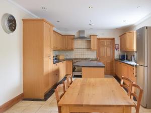 uma cozinha com armários de madeira e uma mesa de madeira em Ty-canol em Ferryside