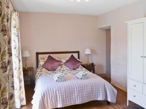1 dormitorio con 1 cama con almohadas moradas en Blackhill Cottage, en Farlam