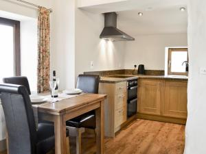 a kitchen with a wooden table with chairs and a sink at Blackhill Cottage in Farlam