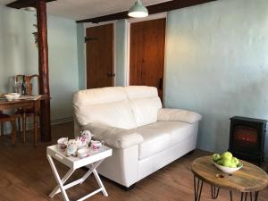 sala de estar con sofá blanco y mesa en Foal Barn Cottages - The Smithy - Spennithorne, en Middleham