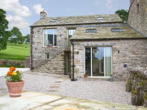 een stenen huis met een glazen deur en een trap bij Brow View Cottage in Ravenstonedale