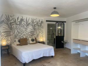 サリ・ソランザラにあるHôtel Restaurant La Caravelleのトロピカルな壁紙の白いベッドが備わるベッドルーム1室が備わります。