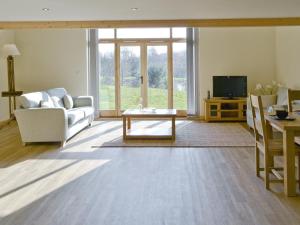 a living room with a white couch and a tv at Orchid Lodge in Hainford