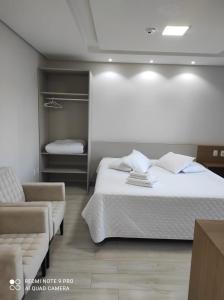 um quarto com uma cama grande e um sofá em Hotel Serrano em Frederico Westphalen