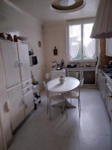 a kitchen with a table and a white refrigerator at Le castel Le Notre in Antony