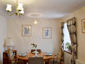 a dining room with a wooden table and chairs at Ross Cottage in Cairneyhill