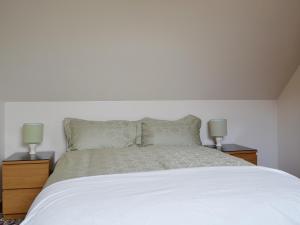 um quarto com uma cama branca e 2 candeeiros em Ross Cottage em Cairneyhill