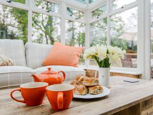 a table with cups and a plate of pastries and flowers at Rectory Cottage in Blankney