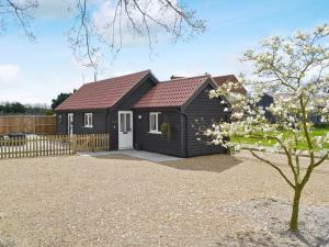 a black house with a white door and a fence at Little Tree Cottage in Felmingham