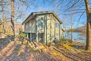 a small house in the woods next to a lake at Lakefront Harrison Home with Sunroom, Deck, and Dock! in Ooltewah
