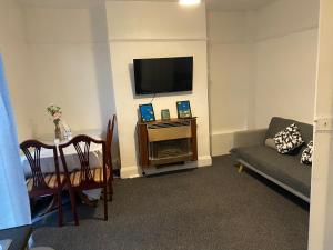ein Wohnzimmer mit einem Sofa, einem Tisch und einem TV in der Unterkunft Room 2 Peaceful stay Near Derby City Centre in Derby