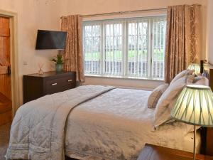 ein Schlafzimmer mit einem Bett und einem großen Fenster in der Unterkunft The Stables in Saint Columb Road Station