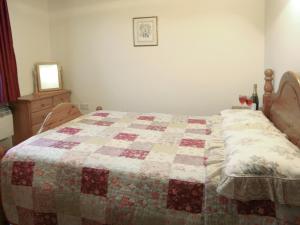 a bed in a bedroom with a quilt on it at Brook View - Hw7477 in Penybont