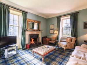 a living room with a fireplace and a tv at Lochenkit Farmhouse in Corsock