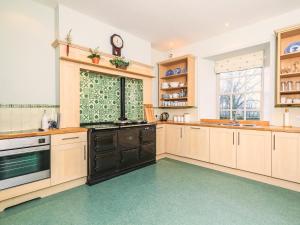 a large kitchen with wooden cabinets and a clock on the wall at Lochenkit Farmhouse in Corsock