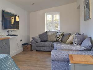 a living room with a couch and a tv at Peartree Cottage Granary in East Witton