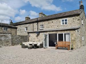 a stone house with a bench and a couch at Peartree Cottage Granary in East Witton