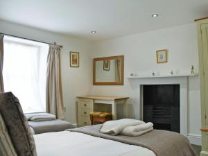 a living room with two beds and a fireplace at Peartree Cottage Granary in East Witton