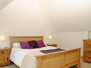 a bedroom with a large bed with purple pillows at Mashers Barn in Bucknell