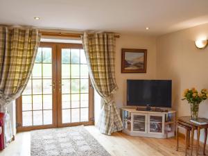 a living room with a flat screen tv and sliding glass doors at The Ploughmans - Uk5531 in Kepculloch