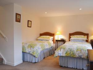 um quarto com 2 camas e uma mesa com um candeeiro em Pear Tree Cottage em Kinlet