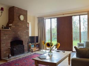 a living room with a fireplace and a table with flowers on it at Coach House in Melton