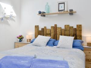 Schlafzimmer mit einem Bett mit blauer Bettwäsche und Kissen in der Unterkunft The Figgery in Wrangaton