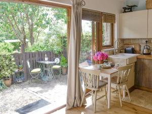 eine Küche mit einem Tisch und Stühlen sowie eine Terrasse in der Unterkunft The Figgery in Wrangaton