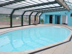 a large swimming pool in a building with awning at Carnethic House - One Acre View in Fowey