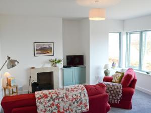 Tigh An Iasgair في Fearnmore: غرفة معيشة مع أريكة حمراء ومدفأة